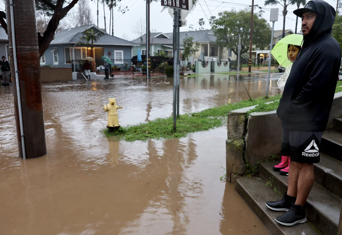 Residents stand along a flooded street in Santa Barbara, California, as a powerful atmospheric river pummels the region. The storm has caused landslides, power outages, and road and airport closures across Southern California. Mario Tama/Getty Images
